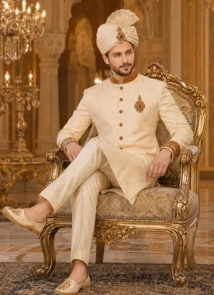 Groom seated in a cream sherwani with a matching turban and khussa