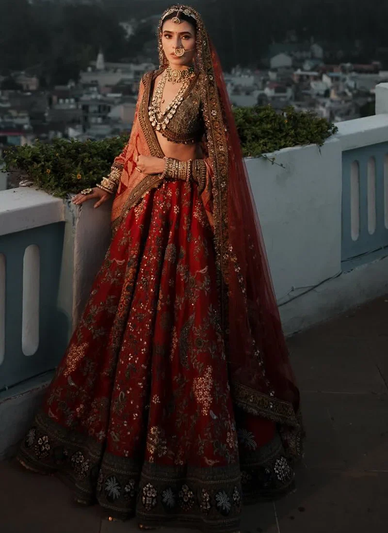Vermilion red bridal lehenga with forest green velvet detailing and traditional multicolour motifs