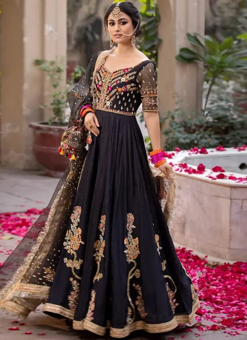 Black Mehndi Pishwas with Kiran-Lace Dupatta Borders Black pishwas in a seated full-flare view with gold-trimmed hem and climbing floral embroidery
