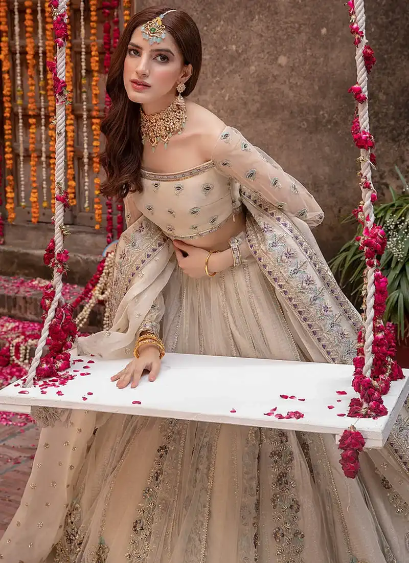 Light champagne Walima lehenga choli, seated front view with embroidered square neckline and floral dupatta border