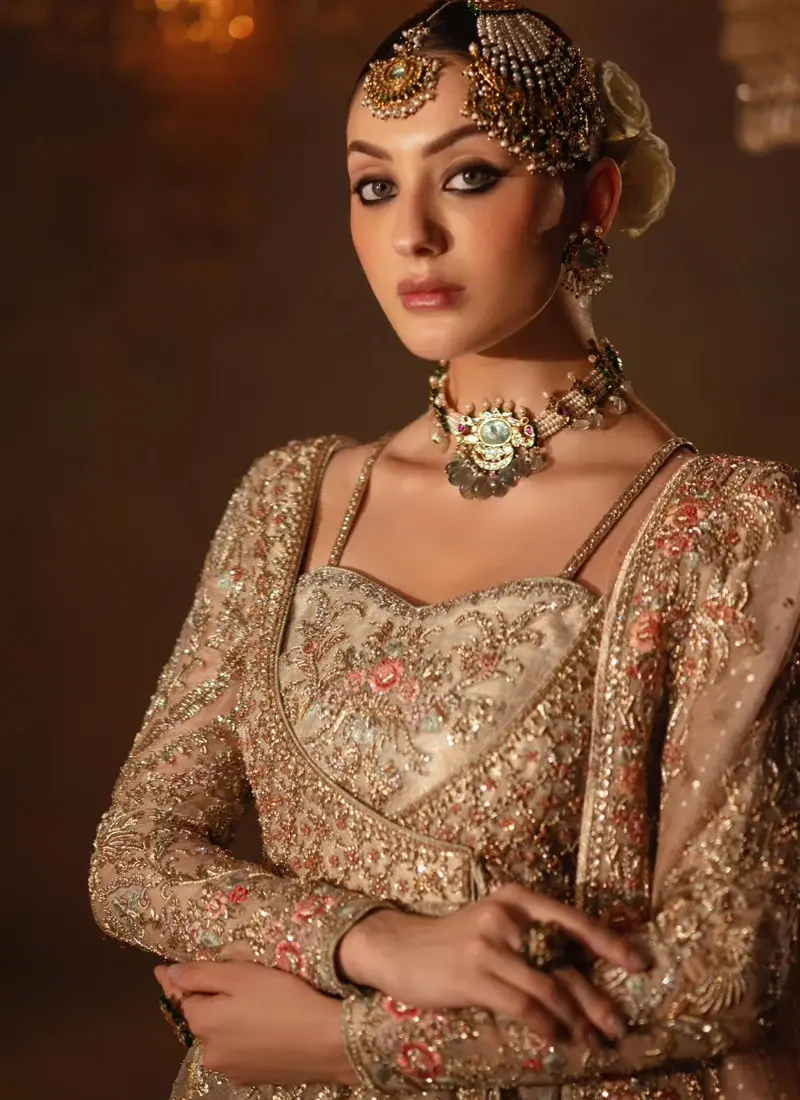 Champagne bridal angrakha and lehenga standing front view with pink floral motifs and sheer dupatta
