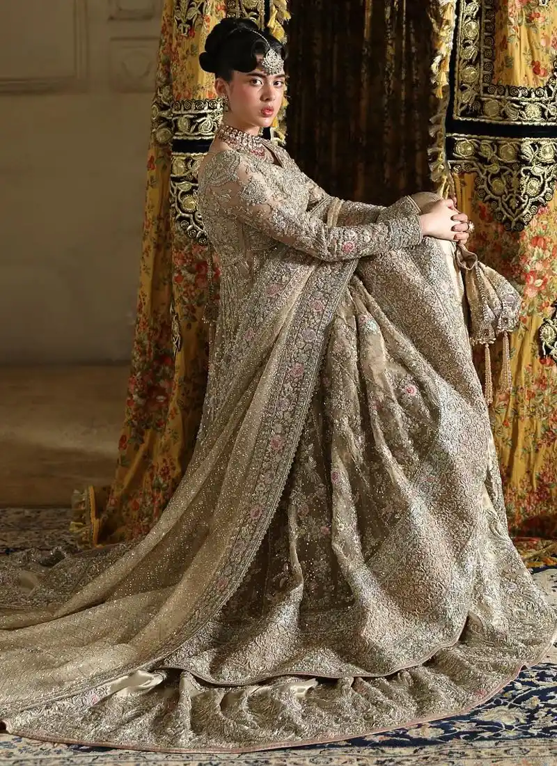 Taupe-gold bridal pishwas and farshi lehenga, seated side view with floral embroidery and sweeping train
