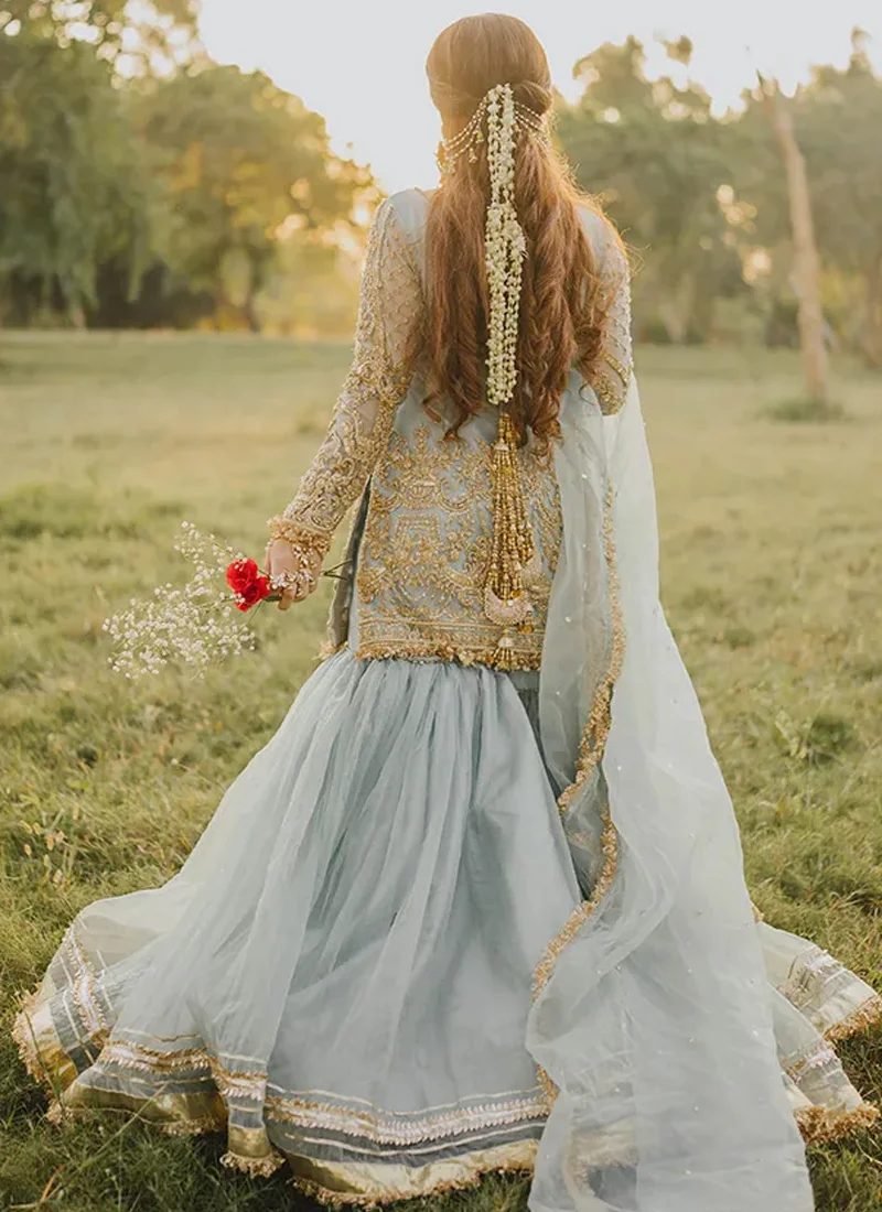 Ice blue gharara suit front view with gold lattice embroidery, ornate shirt hem and flowing flared bottoms