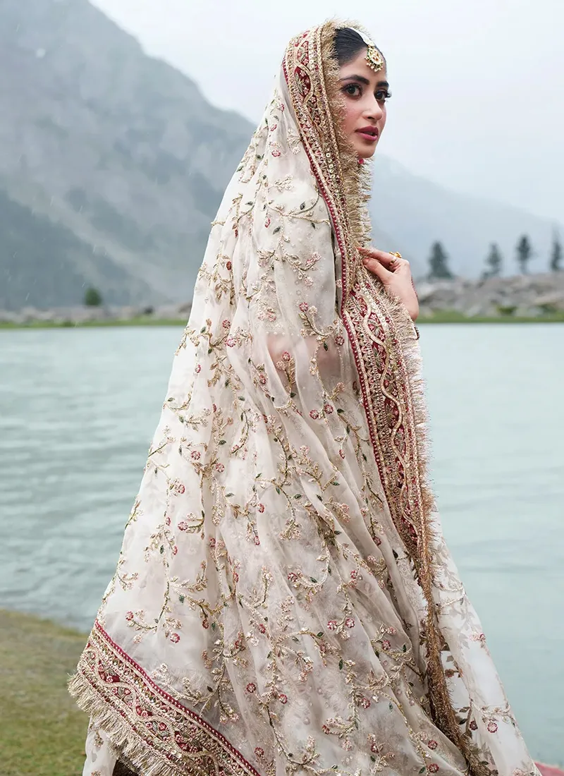 Side profile of the sheer ivory organza dupatta with branching floral vines and a long maroon border finished in gold-toned fringe