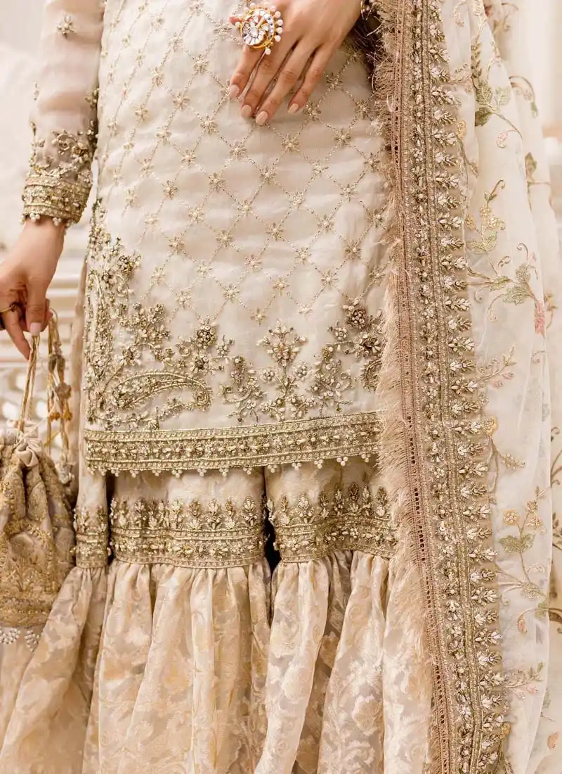 Ivory gharara suit bodice close-up showing round neckline, gold floral embroidery and sheer sleeves