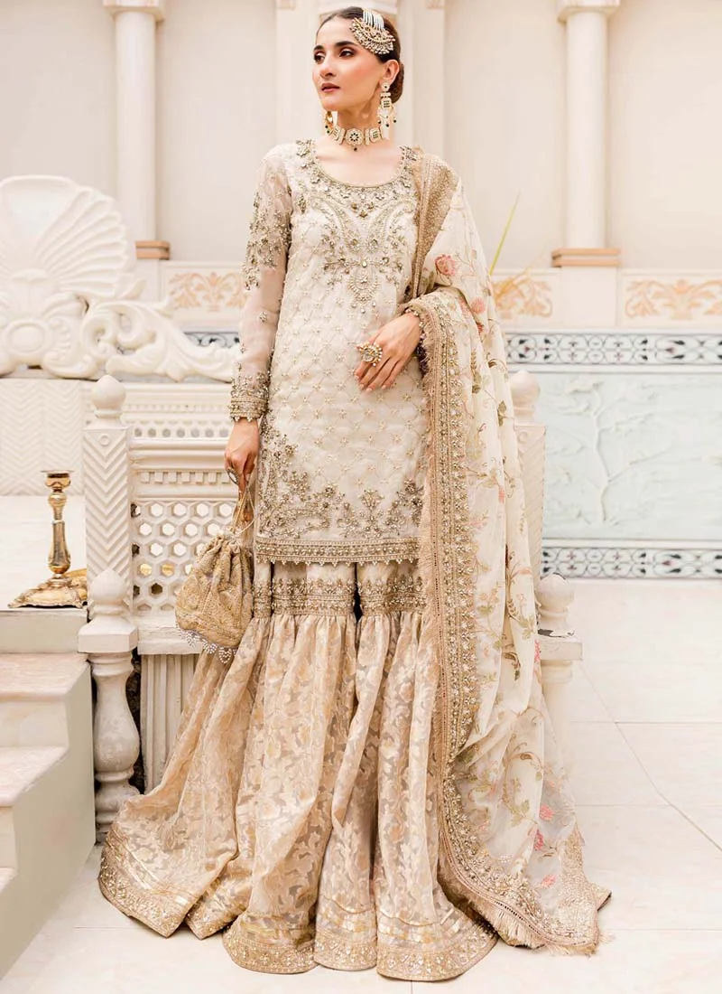 Ivory Nikkah Gharara Suit with Floral Jaal Dupatta Ivory gharara suit hem close-up with gold floral border, gathered gharara tiers and fringed dupatta