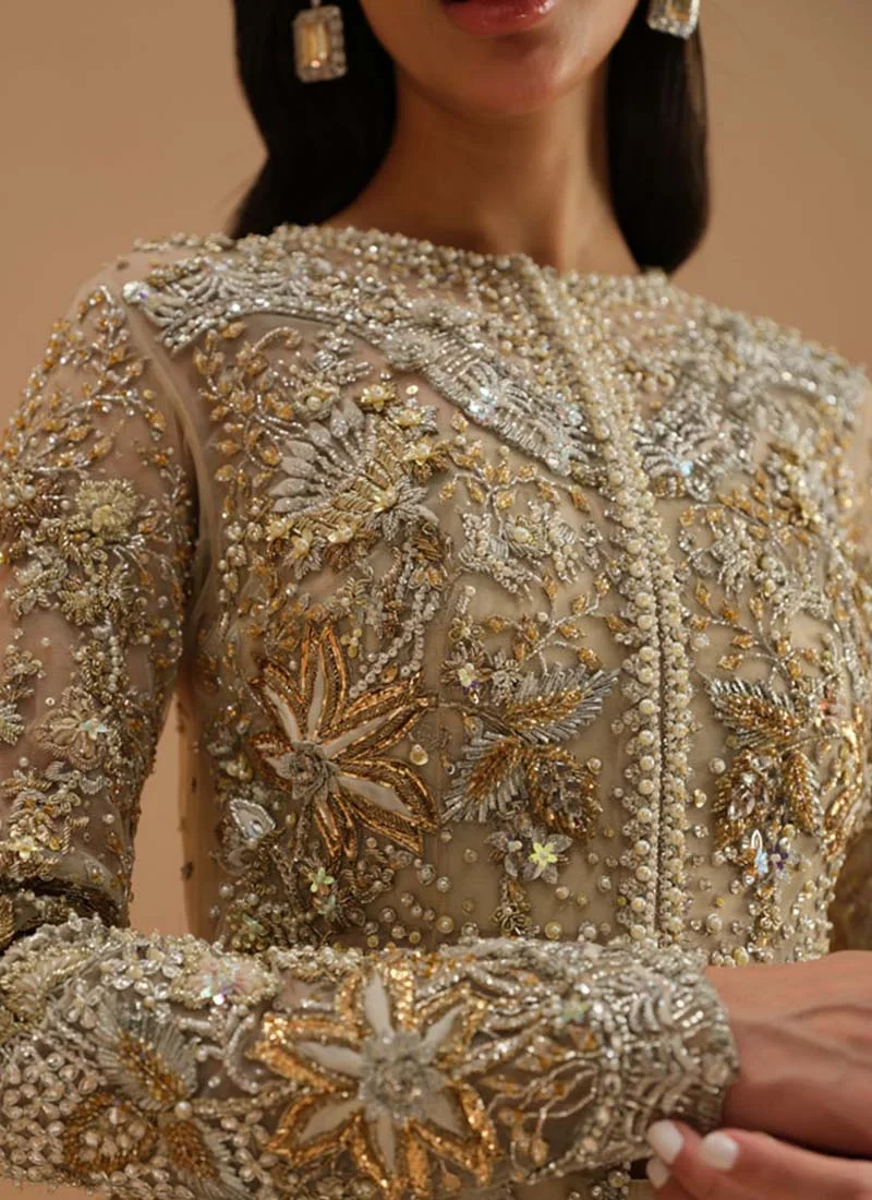 Ivory shirt and lehenga lower-front detail with gold starburst flowers and a scalloped embroidered hem