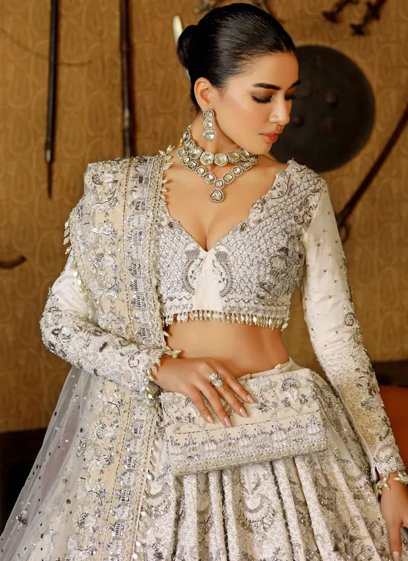 Ivory lehenga choli full front view with silver floral embroidery, flowing net dupatta and layered ruffle hem.