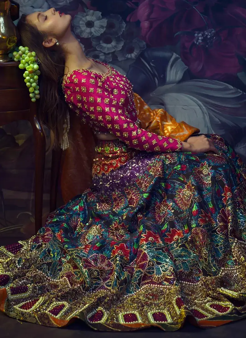 Multicolor mehndi lehenga choli seated front view with vibrant floral embroidery and ornate gold arch borders