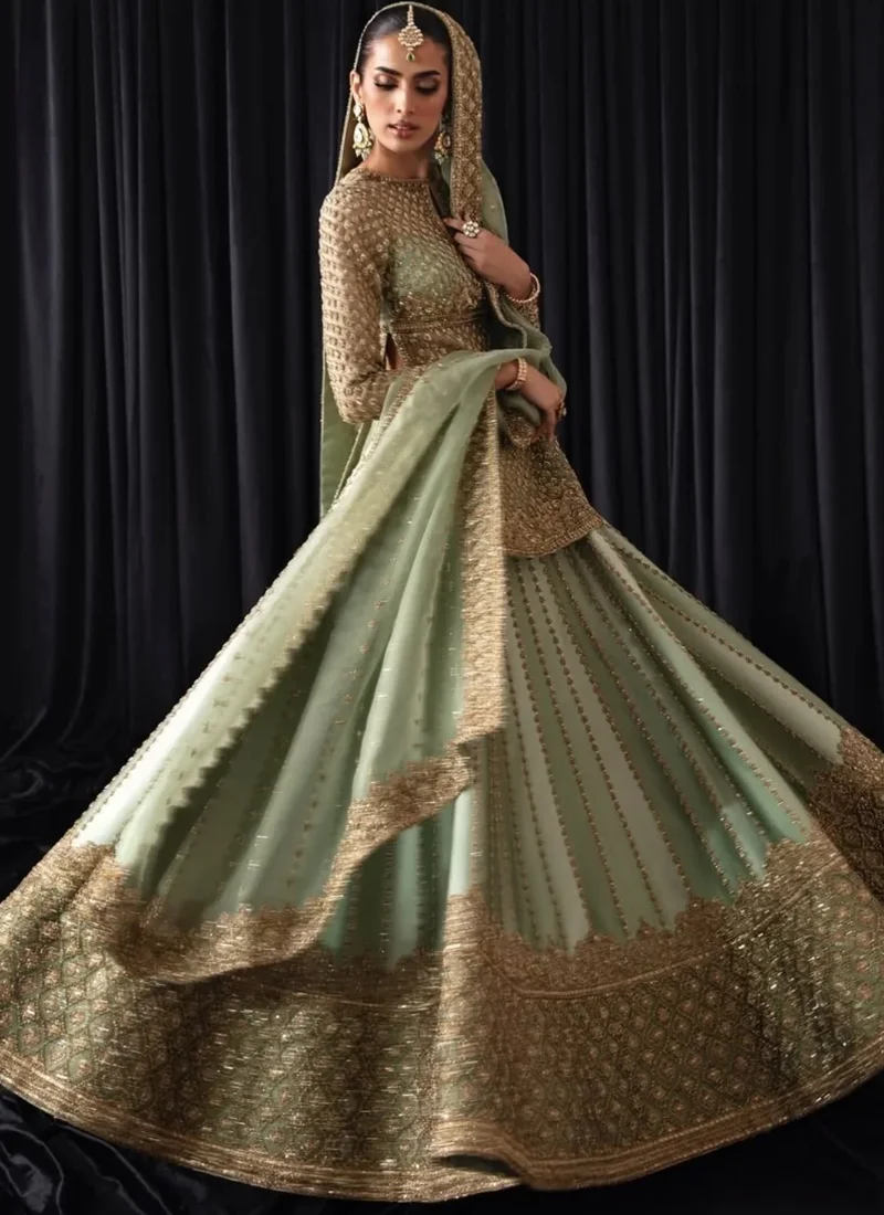 Sage green baraat lehenga kurti in motion with a sweeping skirt and broad gold diamond lattice border