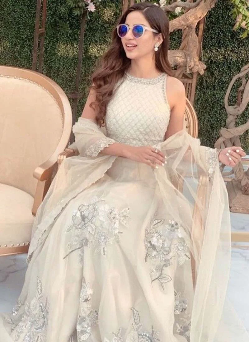 White lehenga choli, full-length three-quarter view with a flared skirt and sheer embroidered dupatta.